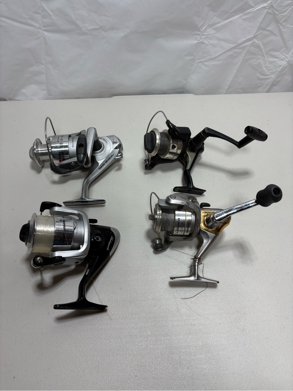 Set of 4 Spinning Fishing Reels in Silver, Black and Gold